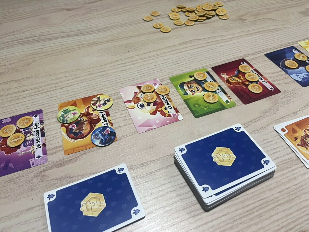 Une partie de La Part du Lion&nbsp;: héritiers, pièces, jetons Courtisan et pioche disposés sur la table.