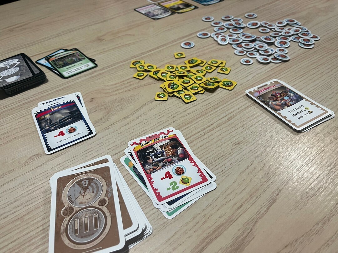 Le centre de la table : les pioches communes, les jetons de nourriture et de colons, une carte Fuite et un Robot serveur